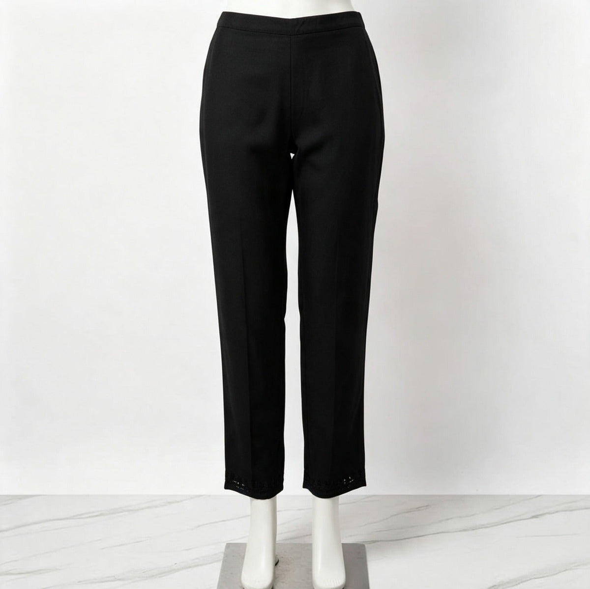 Mannequin display focusing on the matching black trousers of the co-ord set, featuring subtle embroidery detail at the hems against a white marble floor.