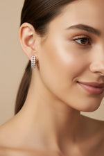 Close-up of 1.5cm silver finish earrings with a curved bar pavé-set with white American Diamonds.