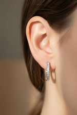 Close-up of 2cm silver finish earrings with a curved bar pavé-set with white American Diamonds.
