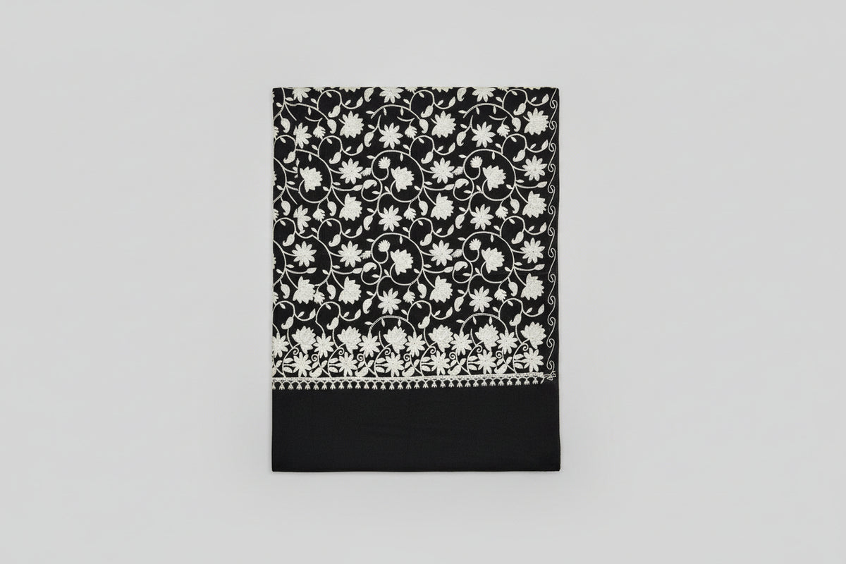 Close-up of a Kashmiri embroidered pashmina scarf featuring floral patterns and tassels.