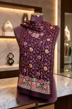 Close-up of a Kashmiri embroidered pashmina scarf featuring geometric and floral patterns primarily in pink and green colors with a gold border.