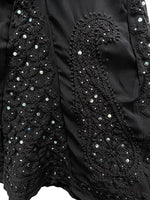 Close-up of a black garment with intricate beadwork and embroidery.