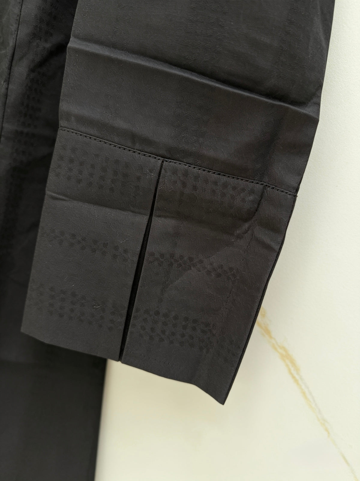 Close-up of a black textured fabric sleeves front cuff design is focused. 