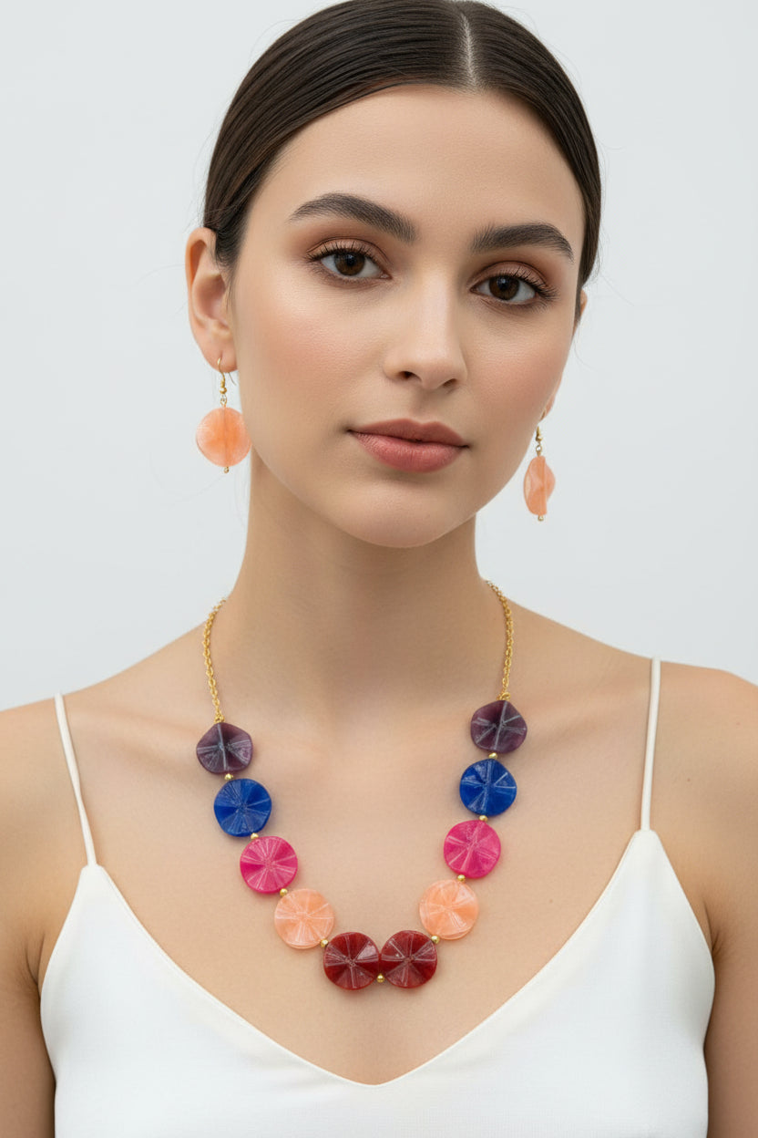 Close-up of a girl modeling a multicolor textured resin jewelry set. The image highlights the marbled finish of the scalloped disc beads and the elegant gold-tone chain, featuring the set's soft peach-colored earrings as a focal point.