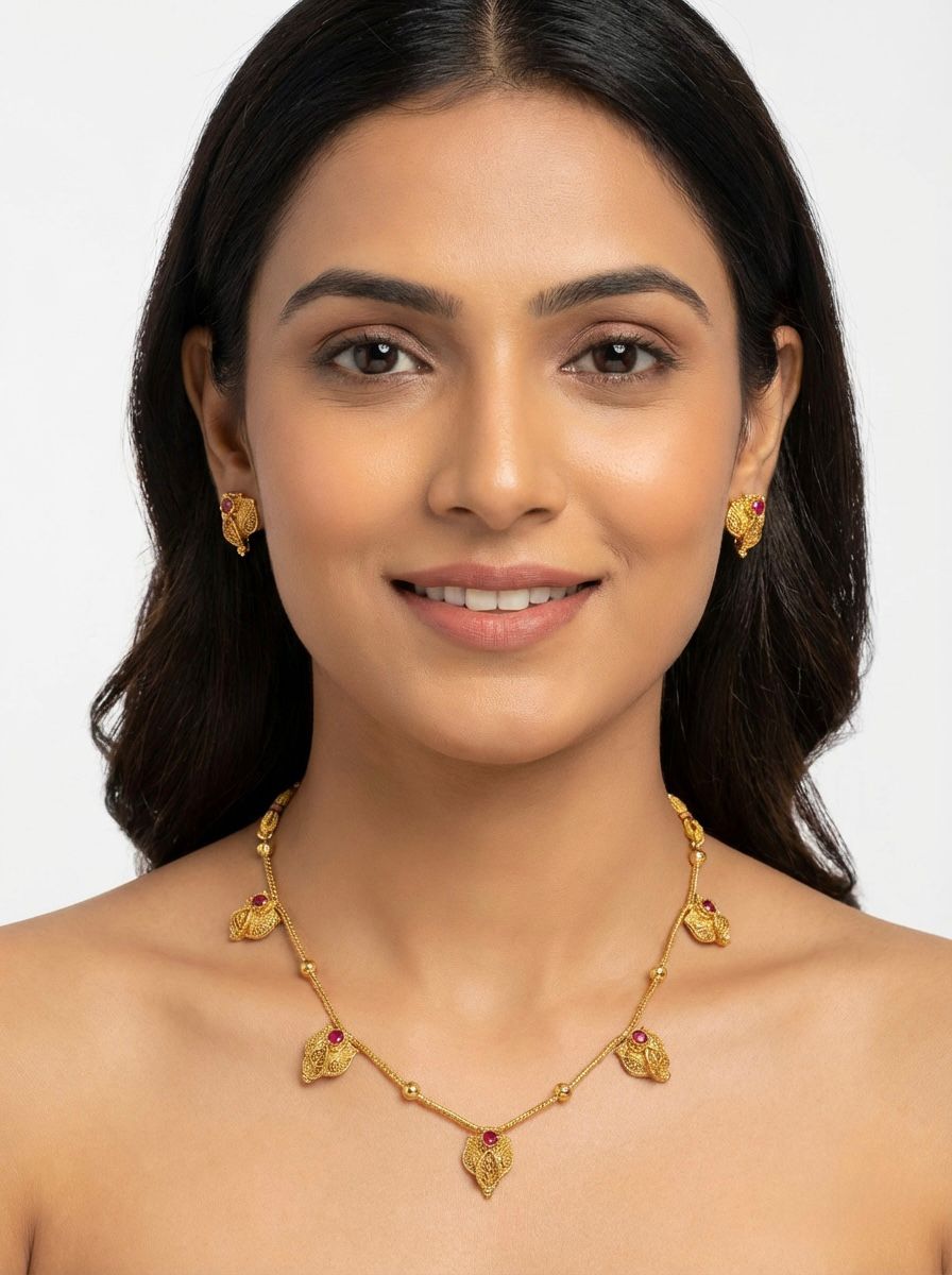  Close-up of a girl wearing the Ruby Red Minakari jewellery set, featuring traditional red enamel charms and gold-toned beads.