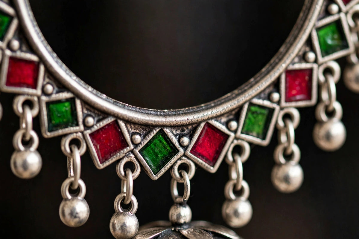 Close-up of the engraved round stud on a silver-tone hoop jhumka earring