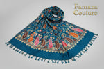 Close-up of a teal blue Kashmiri pashmina scarf with detailed floral embroidery and tassels.