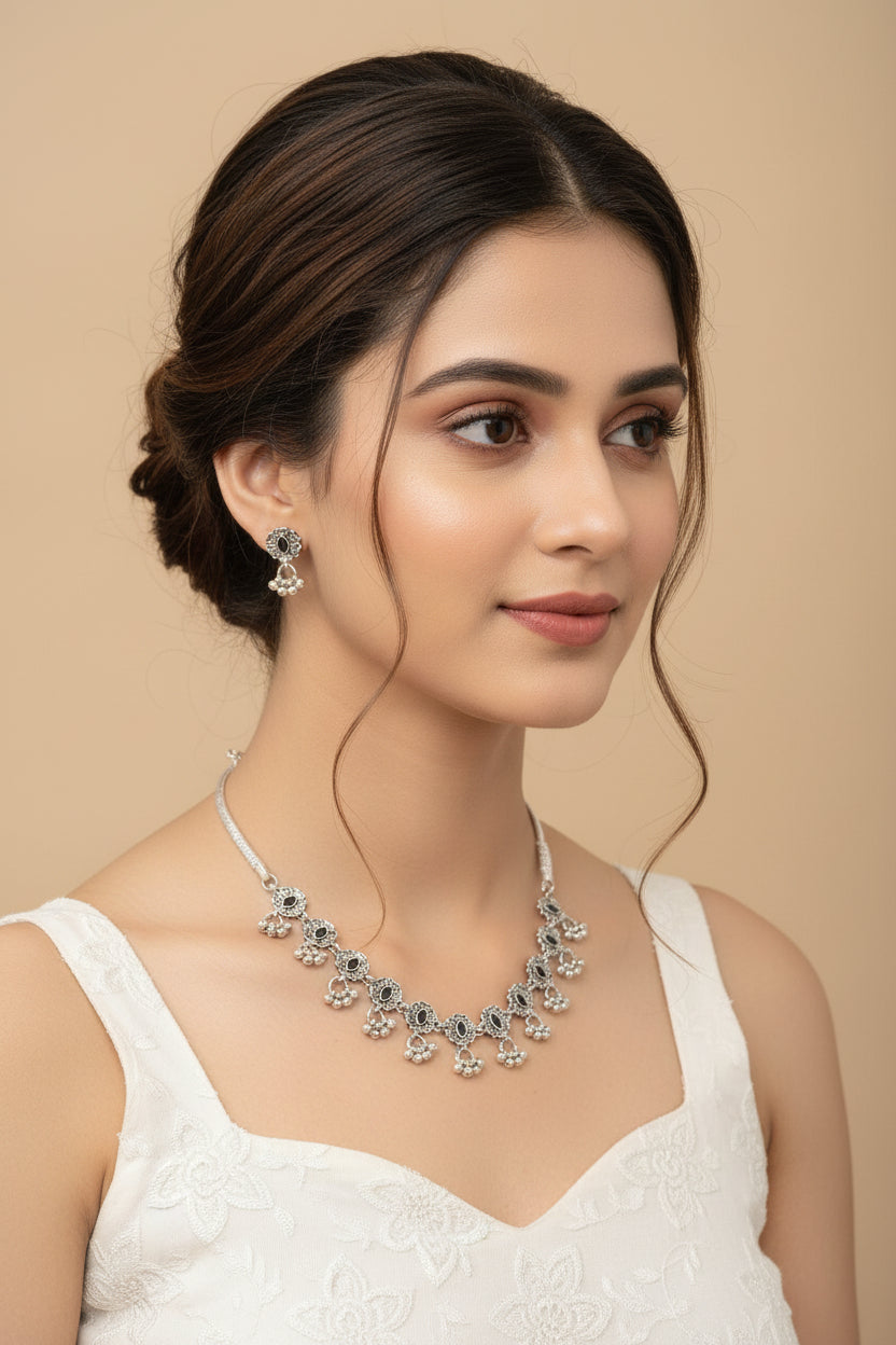  Close-up of a woman wearing a delicate oxidised choker featuring carved floral petals and black gemstone centers.