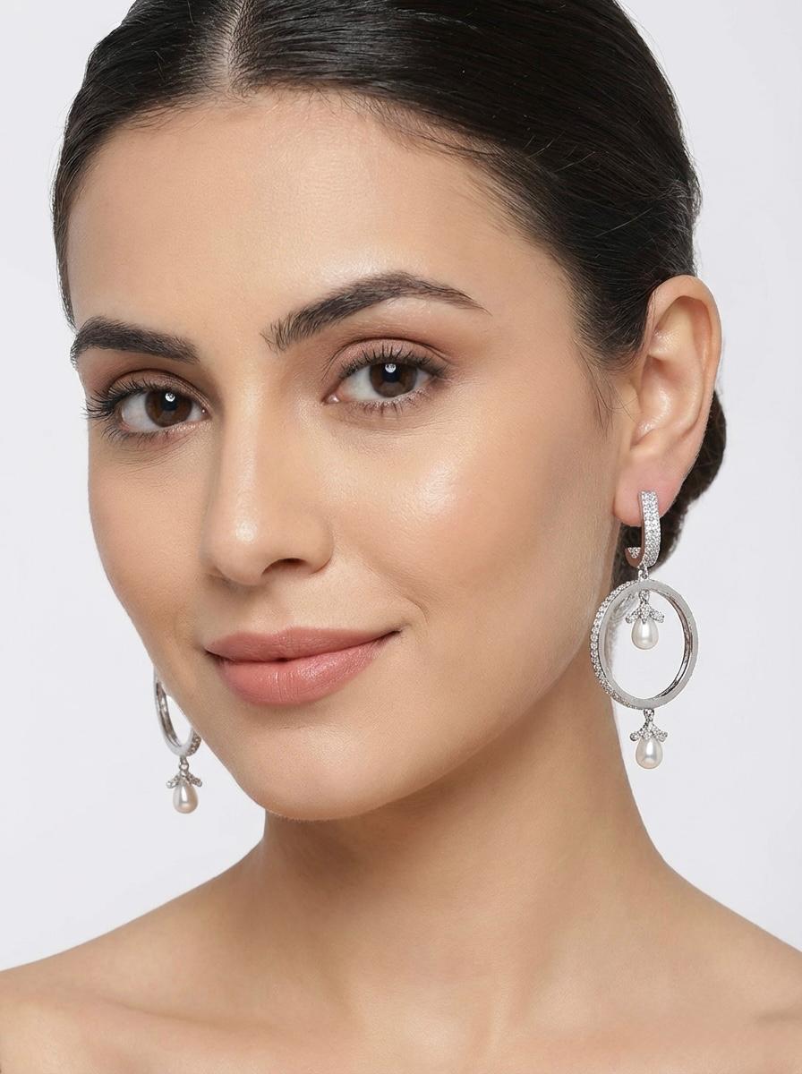 Close-up of a woman wearing elegant silver-tone hoop earrings with dangling pearl accents, showcasing the 6cm length and graceful movement.