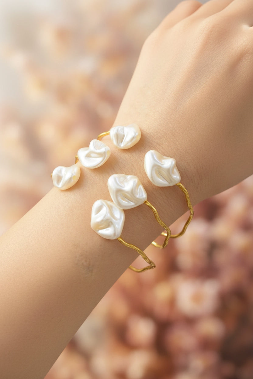 Close-up of a young woman wearing a shimmering 14k gold-plated Mother of Pearl inlay cuff on her wrist, styled with a linen summer dress.