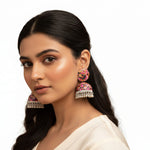 Close-up of artistic plastic jhumka earrings with intricate butterfly motifs and dangling silver-tone ghungroo beads.