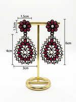 Close-up of black brass teardrop earrings with a vibrant red stone floral stud and matching red stone inlay throughout the teardrop base.