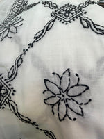 Close-up of black embroidered patterns on a white fabric