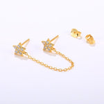 Close-up of crystal-encrusted gold star earrings featuring unique chain detail for a modern, layered look.
