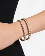 Two diamond-studded bracelets on a person's wrist against a white background