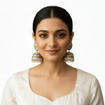Close-up of hand-painted blue and yellow mandala jhumka earrings with silver bead detailing.