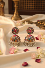 Close-up of lightweight plastic jhumkas featuring intricate miniature portrait artwork and silver beads.