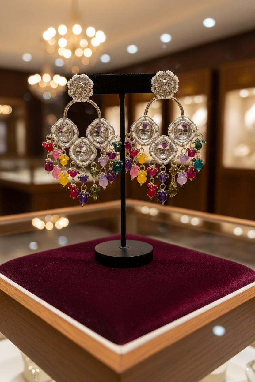  Close-up of silver plated Kundan earrings with white central stones and colorful artisan beads on a jewellery display.