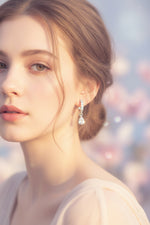 Close-up of the 2cm Lyra silver AD earrings featuring a line of round stones leading to a brilliant teardrop drop.