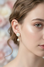 Close-up of the 2cm Serene rose gold AD earrings featuring a circular pavé-set stone stud and a hanging white pearl.