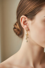Close-up of the 5cm Kaya rose gold AD earrings featuring a floral bud stud with three dangling teardrop stones.