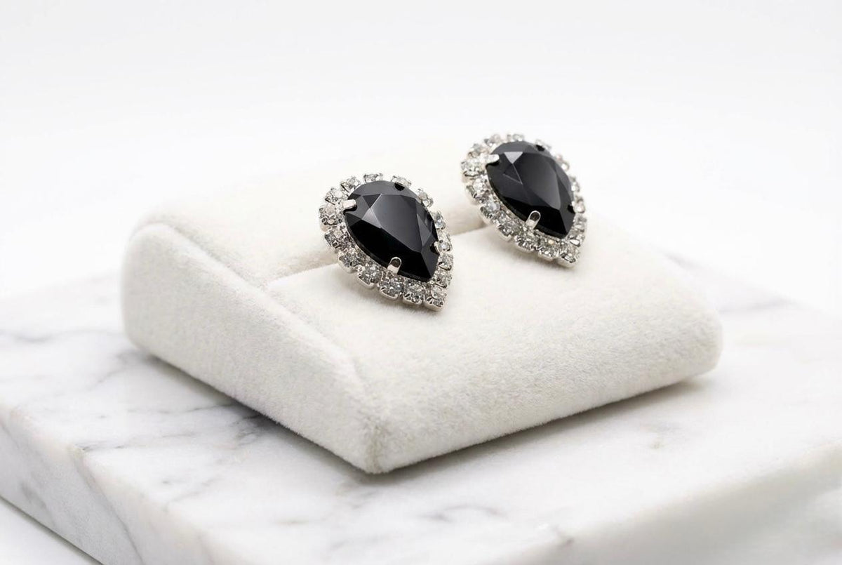Close-up of the brilliant-cut solitaire crystal and the lustrous white pearl drop on a textured fabric background.