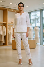 Close-up of white embroidered cotton pants with pockets, showing the texture and design details.