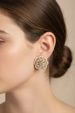 Close-up shot of a woman wearing gold-toned brass Kundan stud earrings with a delicate white nano-beaded border.