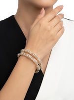 Close-up of a person wearing a silver bracelet on a plain background