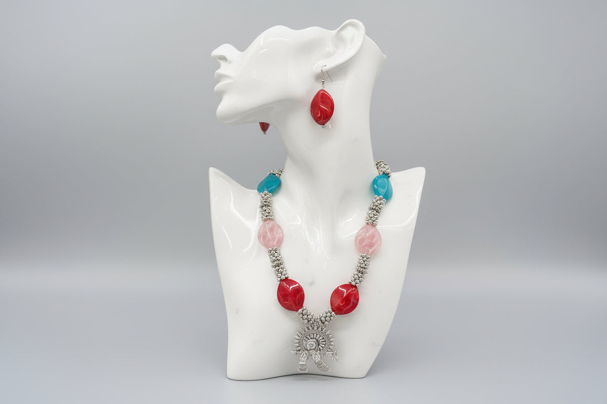 Colourful beaded necklace with red, pink, and blue beads on a black stand.
