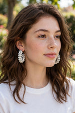 Model wearing creamy ivory hand-woven cluster hoop earrings with polished silver-tone accents and lever-back closure — Famaza Couture bridal & coastal luxury jewelry.
