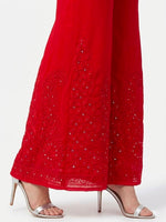 Side view of a crimson sharara featuring detailed Akhandani embroidery and delicate embellishments along the hem, set against a pure white background.
