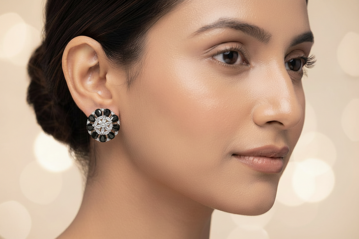 A close-up portrait of a woman wearing a single flower-shaped stud earring with a clear central stone and dark round stones around it, against a soft beige bokeh background.