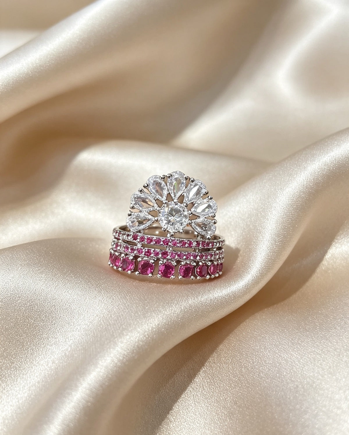 Fan Halo Tiered Ring with white crystal fan halo and silver & fuchsia pink multi-tiered band, luxury designer jewelry resting on cream satin fabric.