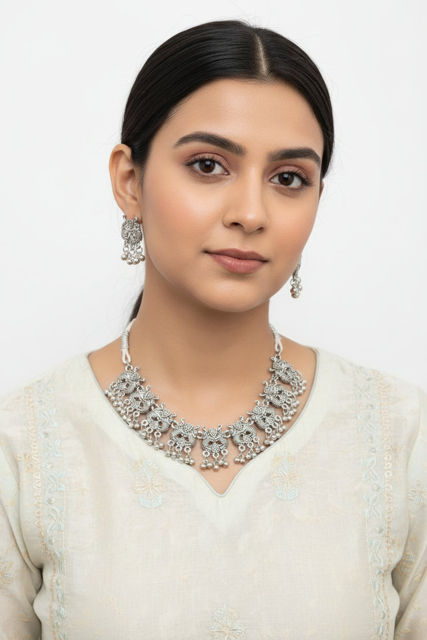 Detailed shot of the intricate symmetrical mandala engravings and tiered hanging silver-tone beads on the oxidised necklace.