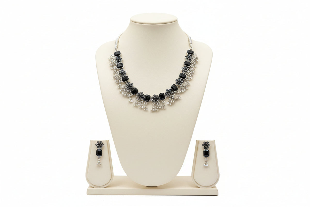 Detailed shot of the symmetrical floral carvings and polished black stone centers on the antique silver-finish necklace.
