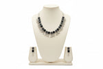Detailed shot of the symmetrical floral carvings and polished black stone centers on the antique silver-finish necklace.