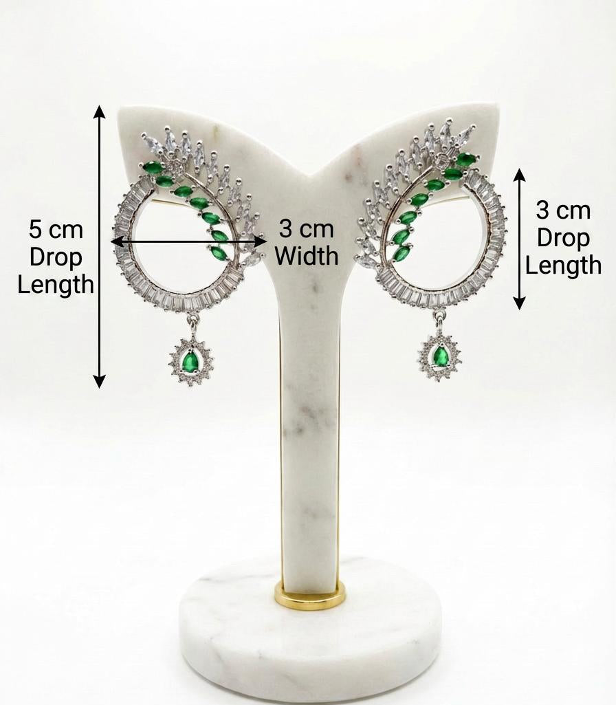 Detailed view of modern silver earrings with a 5cm drop length, showcasing green crystal leaf accents and a central emerald teardrop pendant.