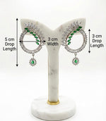Detailed view of modern silver earrings with a 5cm drop length, showcasing green crystal leaf accents and a central emerald teardrop pendant.