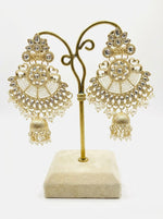  Dull gold ethnic earrings displayed on a stand, showing the intricate kundan-style work and bottom jhumka drop.