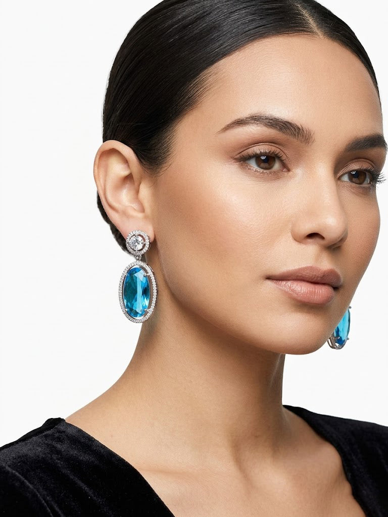 Blue oval statement earrings with diamond-style halo setting, modeled to show size and style, ideal for formal evening wear.
