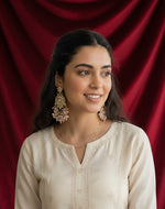 Elegant model wearing statement rose gold American Diamond earrings against a rich red velvet background, highlighting the posh jewellery aesthetic for modern wedding guests.