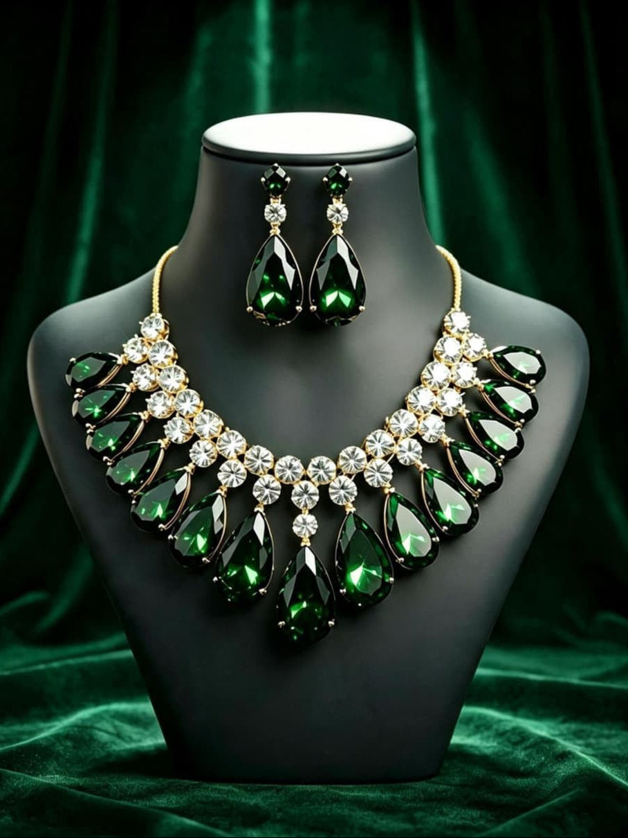 Emerald Cascade Teardrop Jewelry Set displayed on black jewelry stand — statement necklace with cascading pear-shaped emerald green gemstones and sparkling clear cubic zirconia accents, paired with matching drop earrings, set against luxurious emerald green velvet background.
