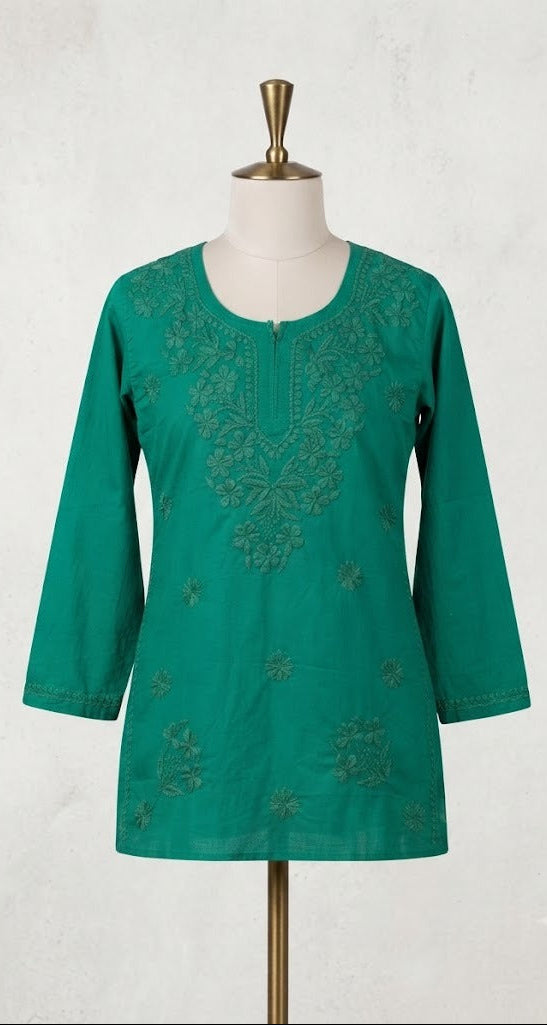  A vibrant green short kurti displayed on a dress form, featuring tonal floral embroidery around the split neckline, long sleeves, and scattered floral motifs on the lower front.