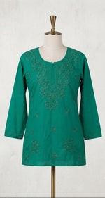  A vibrant green short kurti displayed on a dress form, featuring tonal floral embroidery around the split neckline, long sleeves, and scattered floral motifs on the lower front.