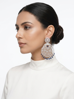 Model showcasing majestic silver chandelier earrings adorned with clear pave crystals and sapphire blue teardrop accent stones against a clean white background