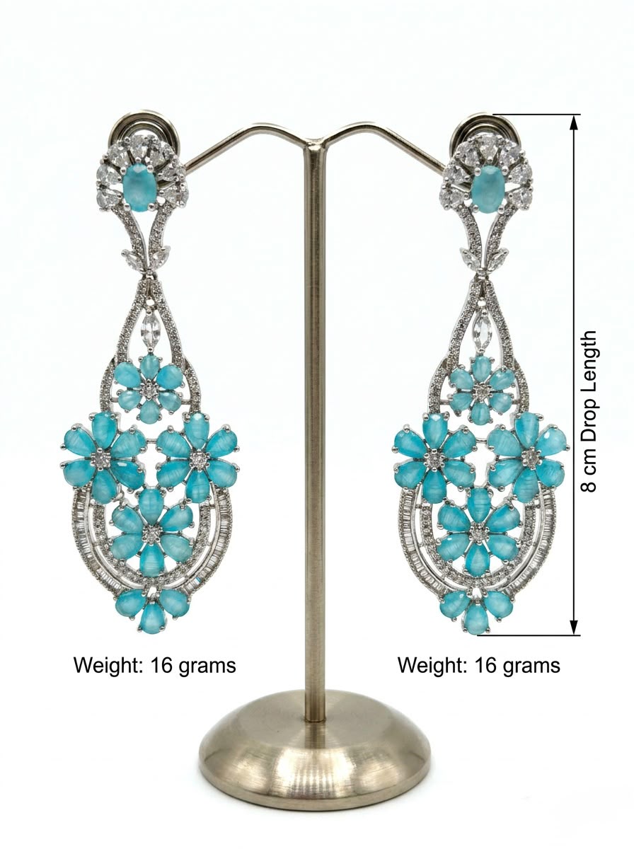 A pair of ethereal teal blossom statement earrings on a display stand.
