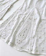 A flat-lay view of a pair of ethereal white sharara pants, showcasing delicate paisley motifs and intricate Bakhiya embroidery detail, set against a clean white background.