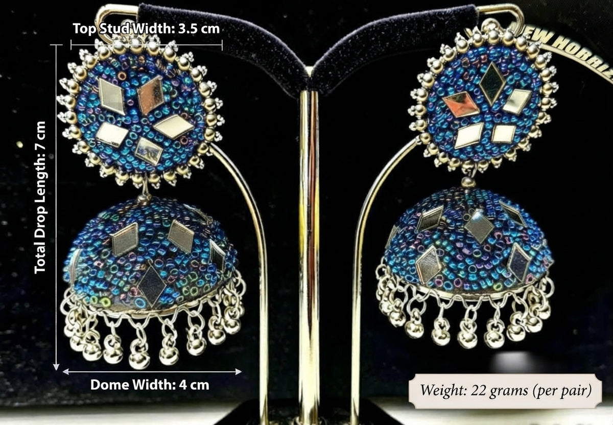 Cobalt blue iridescent mirror bead jhumka — 7cm total drop, 3.5cm top stud, 4cm dome, 22g pair — displayed on gold stand with black velvet backing — Famaza Couture.