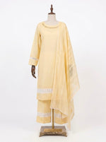 A front studio photograph of a three-piece pastel yellow plain cotton shalwar kameez suit by Famaza Couture, displayed on an artistic mannequin stand. The set includes a solid kurta with fine neckline stitching, trousers featuring intricate white lace inserts and pintuck pleat detailing at the hem, and a matching patterned sheer dupatta draped over the shoulder, against a white background.
